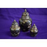 Three graduated lidded brass urns, having enamel detailing.