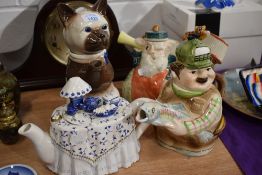 Four novelty tea pots including Tony Wood cat design, a Coronation deaf man and the village