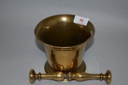 A 19th century brass mortar in typical fluted bell form with a double baluster and central knop