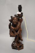 A vintage Japanese wooden carved lamp base of a monk with fruit baskets. 36cm tall.