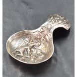 A George V silver caddy spoon, the bowl with embossed interior scene, the handle with foliate