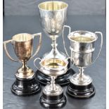 A group of four silver trophies, various dates, makers and designs, each with ebonised socle,