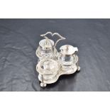 An Edwardian silver and cut-glass condiment set, having a raised and shaped central handle over