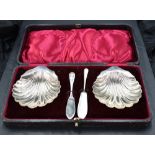 A cased pair of late Victorian silver butter dishes, of scallop shell form with shaped lip handle