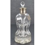 A white metal mounted glass decanter, having an associated glass stopper over the flared and bead