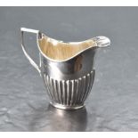 An Edwardian silver helmet-form cream jug, with angular handle and half gadrooned body, marks for