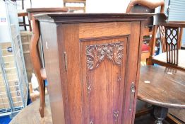 A Victorian mahogany pot cupboard, the panelled door having carved thistle decoration