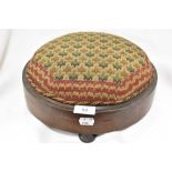 An antique button shaped foot stool with embroidered top.