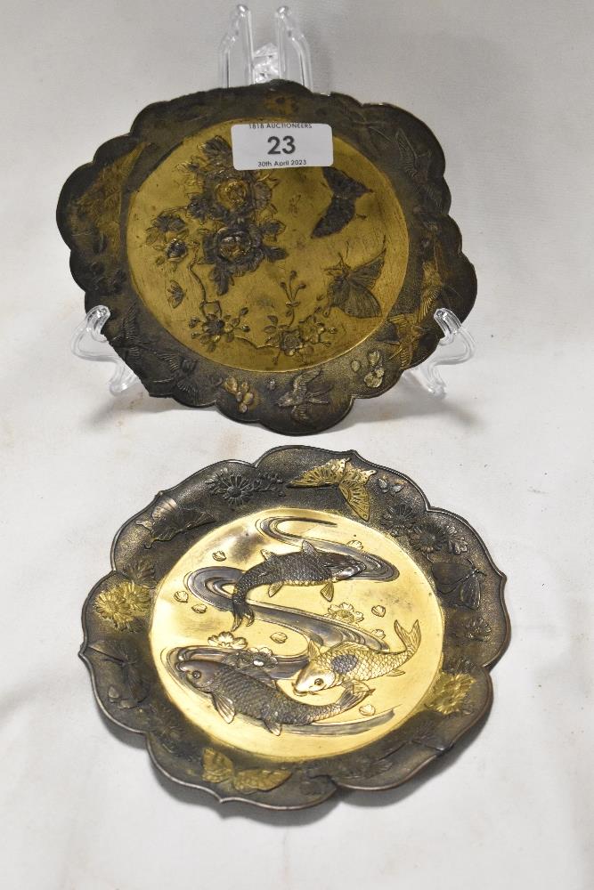 Two antique Japanese mixed metal dishes embossed with designs of two carp swimming and a pair of