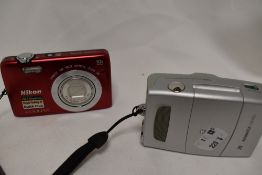 Two cameras. A Nikon Coolpix S6700 camera in original box with charger and a Advantix T570 camera