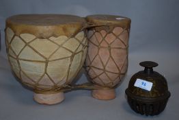 An Indian style tabla drum in terracotta an animal hide with an Indian brass bell.