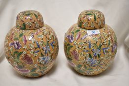 A pair of early 20th century peach ground ginger jars decorated with floral patterns.