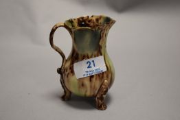 An 19th century English slipware jug on tripod feet decorated with faces. In very fine condition 9cm