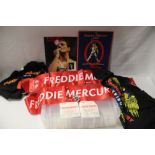 A lot of Freddie Mercury items with scarves and t-shirts and a badge and programmes with ticket