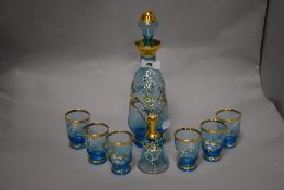 An Egyptian hand-decorated blue glass liqueur set, comprising decanter, six glasses and bell of