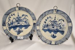 Two 18th century Delftware plates, having Oriental designs of pagodas and lakes.