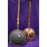 Two antique copper bed warming pans with turned wood handles.