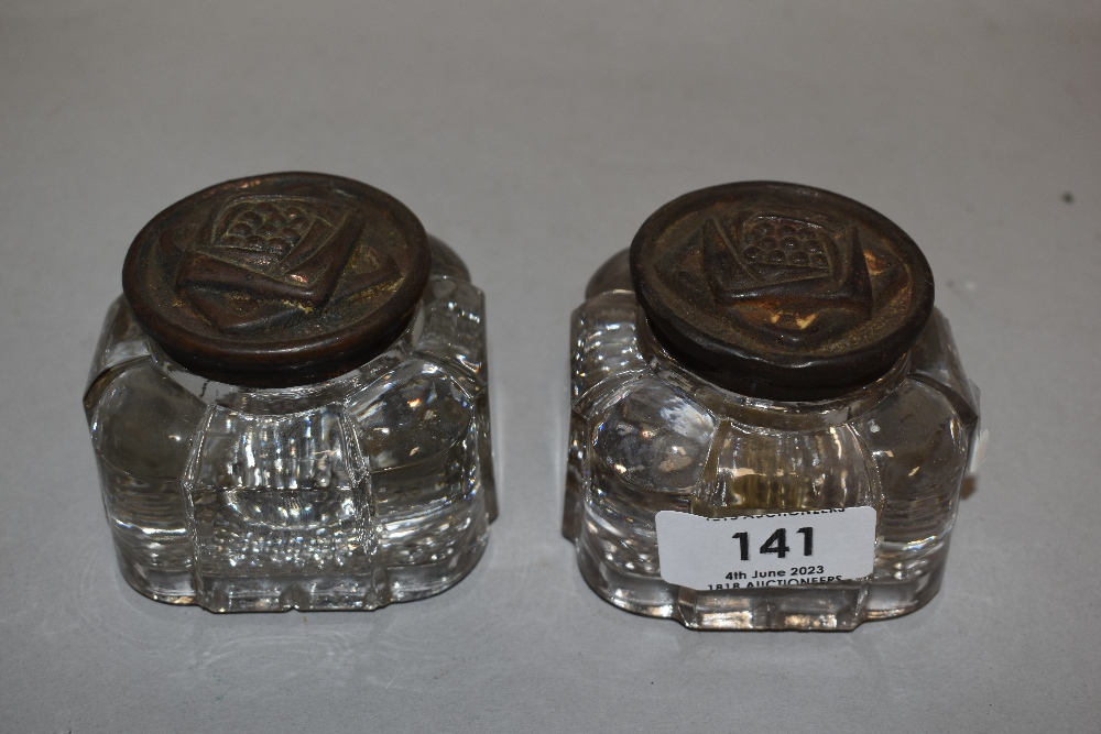 Two late 19th/ early 20th century pressed glass ink wells having embossed metal lids in the Rennie