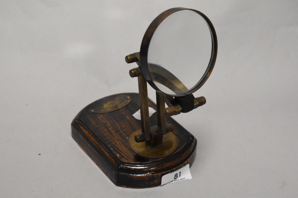 An early 20th century desk top magnifying glass on wood plinth, with metal label for Bausche and