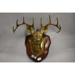 A mid 20th century brass stags head of wooden wall mountable shield.