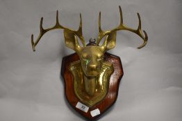 A mid 20th century brass stags head of wooden wall mountable shield.