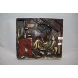 A wax plaque depicting scene of man in bed holding umbrella, surrounded by books by an