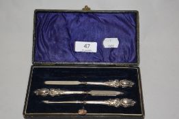 A late Victorian manicure set in case, having hallmarked silver embossed handles.