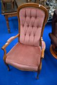 A reproduction stained frame armchair with pink dralon upholstery