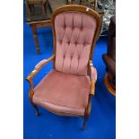 A reproduction stained frame armchair with pink dralon upholstery