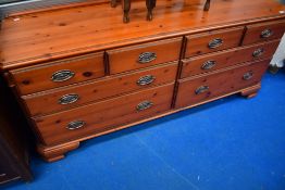A modern red stain pine wide chest or sideboard having four short drawers over two banks of two