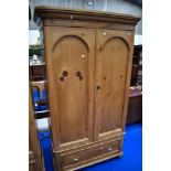 A stripped pine wardrobe in the Victorian style having drawer base