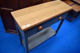 A modern hall table having natural top with grey drawers and frame