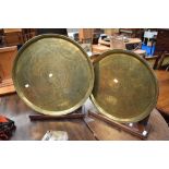 Two eastern brass trays of circular form with stained frame stands
