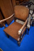 An early 20th Century oak framed armchair with studded leather back and seat , cup and cover type