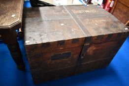 An antique shipping trunk with various names and brass label to side