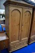 A stripped pine wardrobe in the Victorian style having drawer base