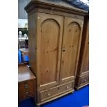 A stripped pine wardrobe in the Victorian style having drawer base