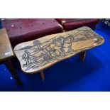 A traditional golden oak coffee table having carved ploughing decoration, width approx. 111cm