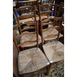 Two pairs of rush seated kitchen chairs having shaped ladder backs