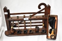 An unusual stained oak pipe rack, formed as a five bar gate, with six divisions and six pipes.