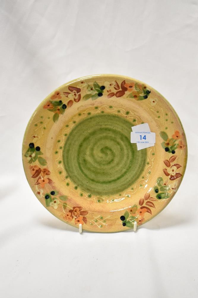 A glazed earthenware plate, the border decorated with repeating floral motifs, and having a green