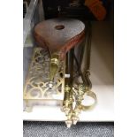 A vintage brass trivet, a set of wooden bellows, and a companion set.