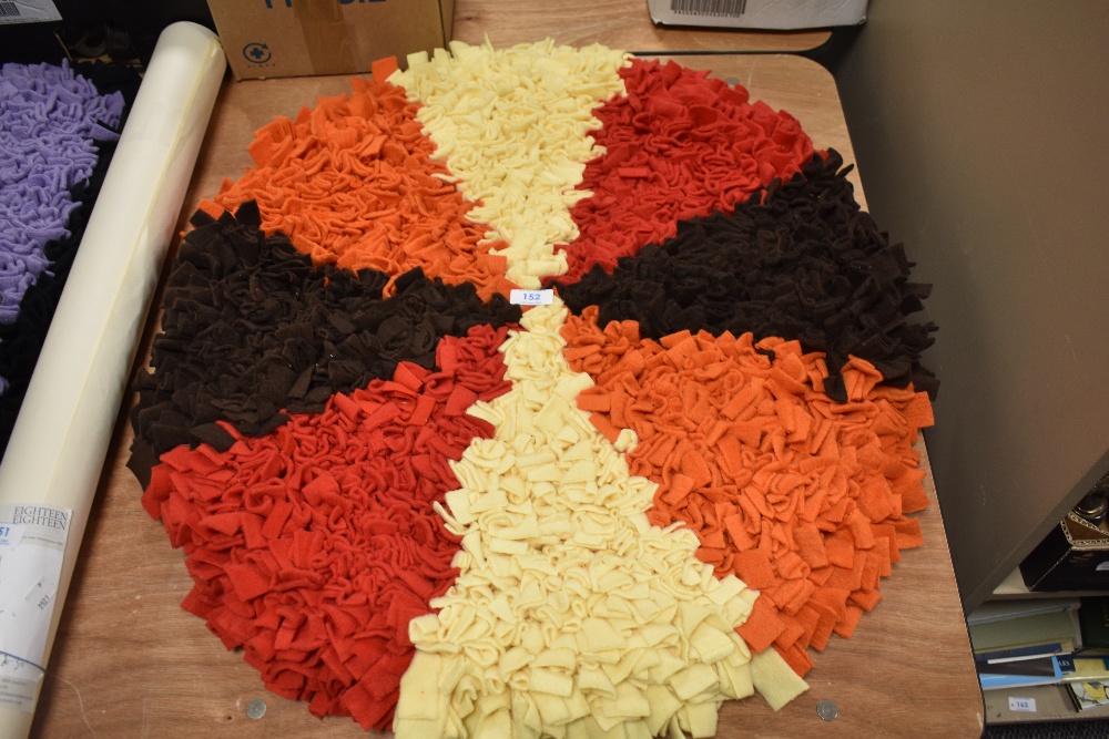 An as new, handmade circular peggy/ proddy rug in orange, brown, red and yellow.