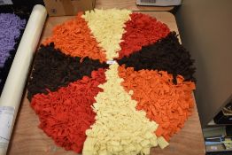 An as new, handmade circular peggy/ proddy rug in orange, brown, red and yellow.
