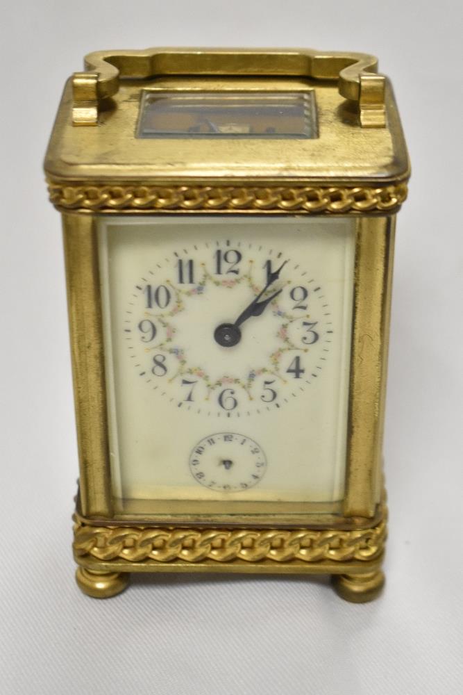 An early 20th Century French carriage clock, with shaped handle, bevelled glass case, a hand painted