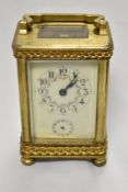 An early 20th Century French carriage clock, with shaped handle, bevelled glass case, a hand painted