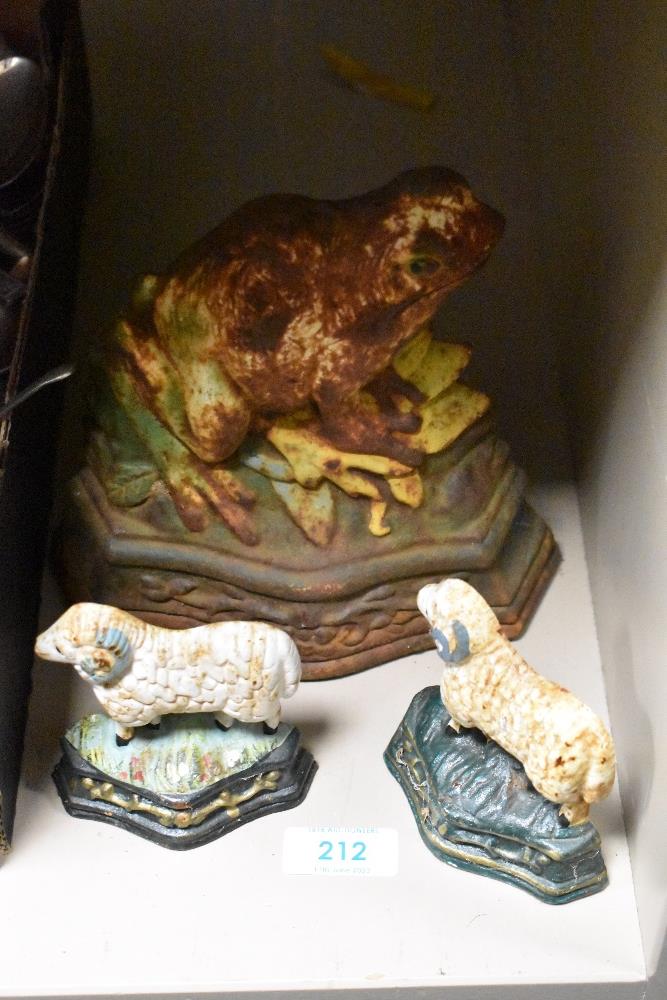 A cast iron door stop in the form of a frog and two smaller examples in the form of sheep.