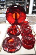 A collection of mid century ruby glass cups and saucers, plates and sugar basin.