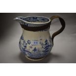 An antique blue and white jug having traditional oriental style transfer pattern, having metal