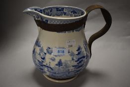 An antique blue and white jug having traditional oriental style transfer pattern, having metal